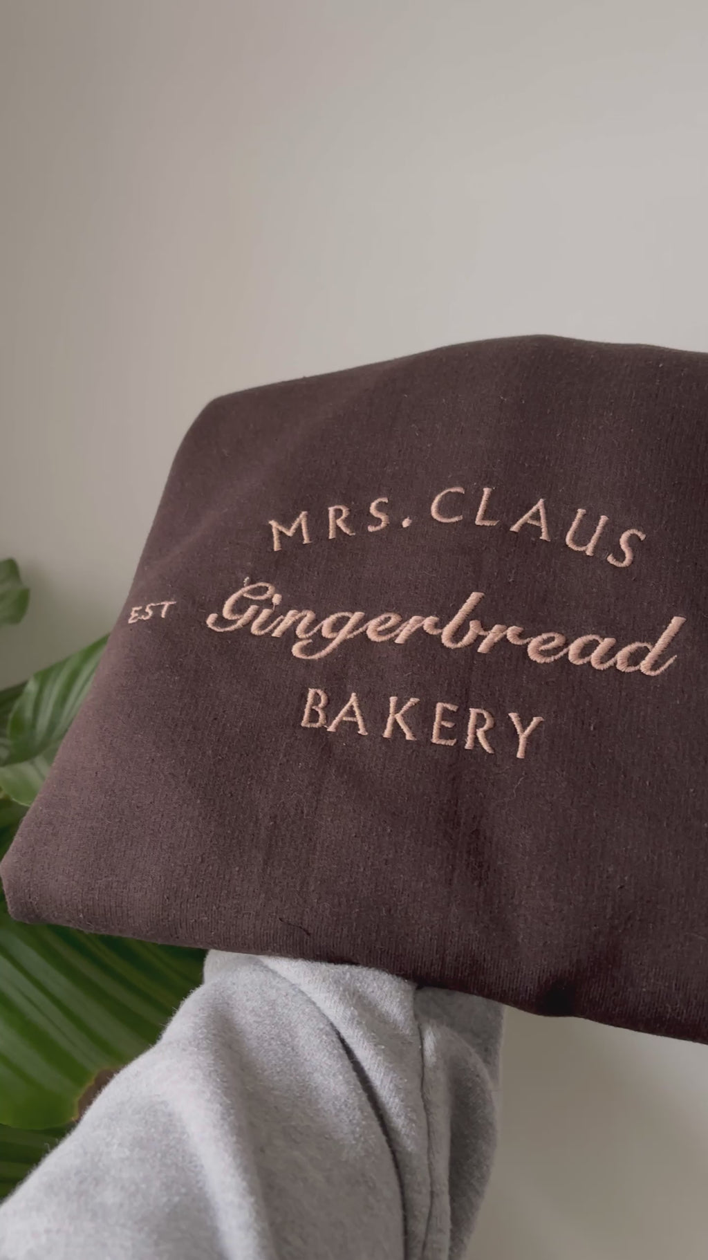 Ein kuschelig weicher Sweater für die kalte Jahreszeit. Bestickt mit Mrs. Claus Gingerbread Bakery in einem Karamell Ton.